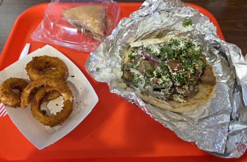 Pita Bite gyro with tzatziki, feta and parsley, onion rings and baklava on a tray
